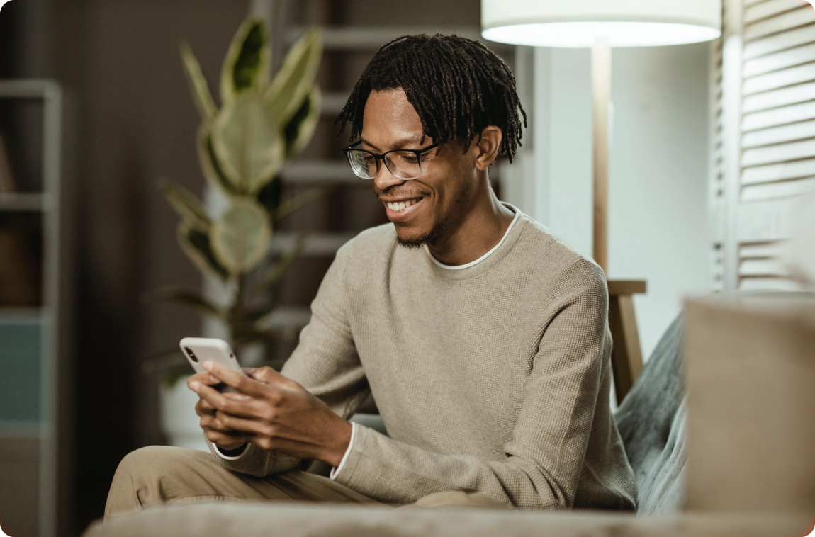 homem-negro-com-moleton-bege-mexendo-no-celular e sorrindo